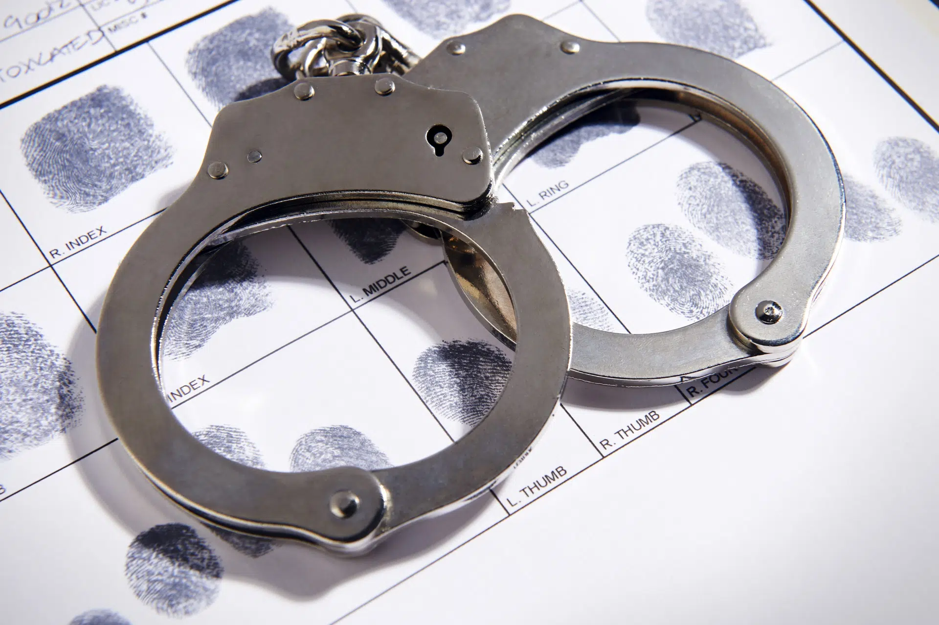 Silver handcuffs placed on fingerprint identification sheet
