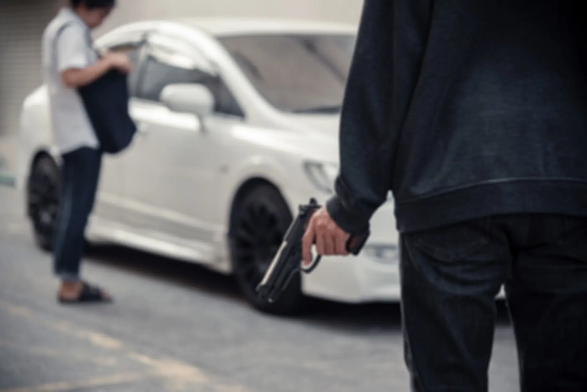 Person holding a gun near a white car.