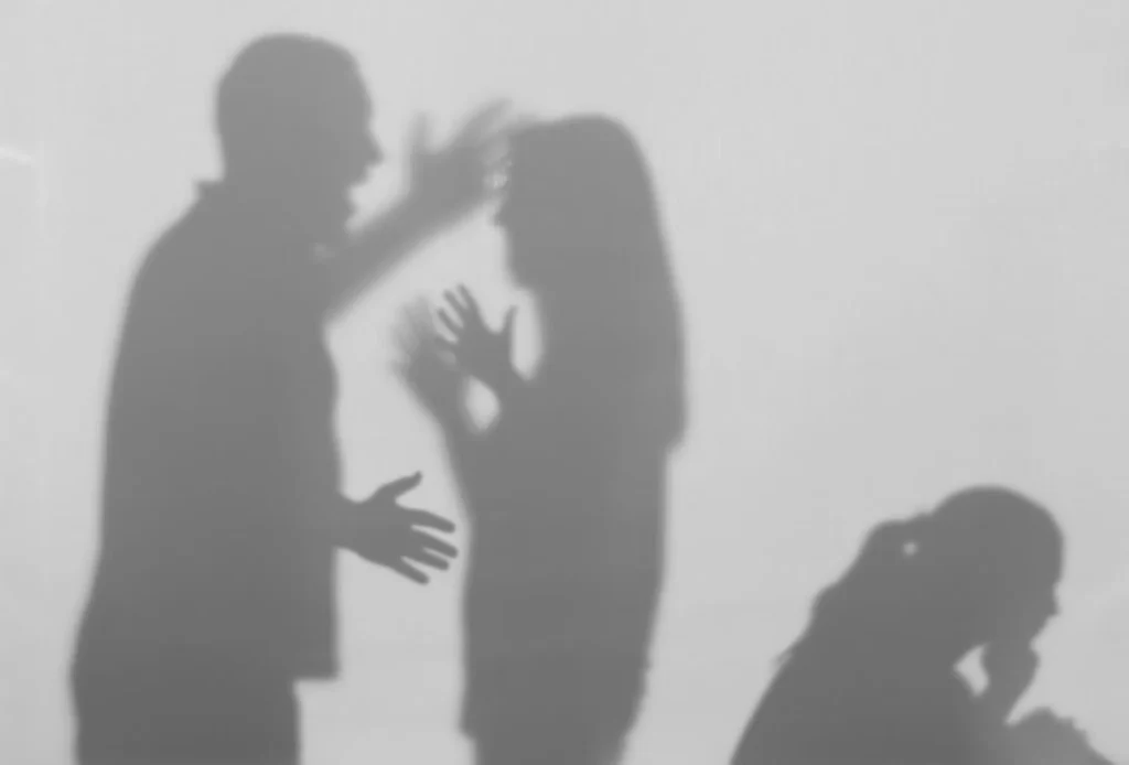 Silhouettes of people in a heated argument with a distressed figure.