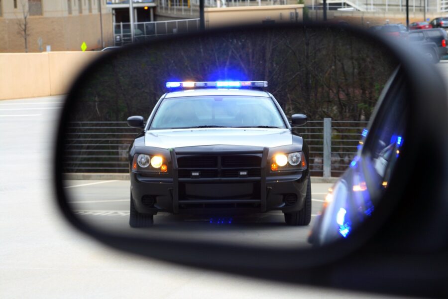 A police car's reflection in a car's rear view mirror | DUI Homicide Defense Lawyer | Wegman & Levin