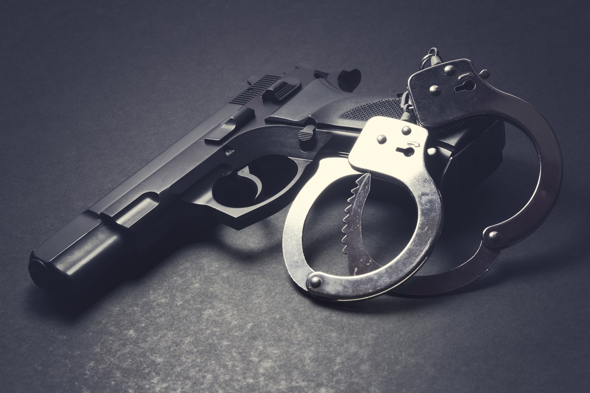 Handgun with Handcuffs on Dark Background | Criminal Attorney in Los Angeles | Wegman & Levin